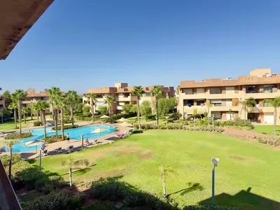 a view of a park with a pool and buildings at Appartement with a view on the pool in Marrakech