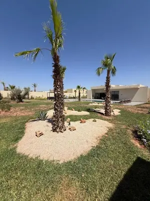 two palm trees in a field with a building at Villa ALIYAH in Marrakech