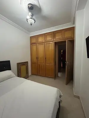 a bedroom with a white bed and wooden cabinets at Appartement 2 Chambres Confortable à Jnane Awrad Calme & Sécurité in Marrakech