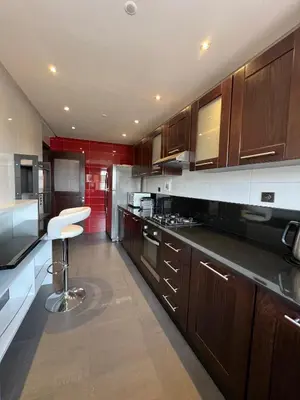 a kitchen with wooden cabinets and a stool in it at GUELIZ 2 chambres 1 terrasse proche majorelle in Marrakech