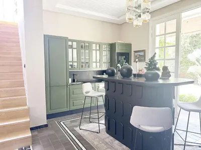 a kitchen with green cabinets and a counter with stools at Yasira in Marrakech