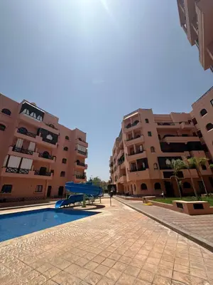 a swimming pool in front of two apartment buildings at Apparemment première village in Marrakech