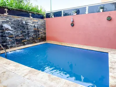 a swimming pool in a backyard with a red wall at Villa with private pool in Marrakech