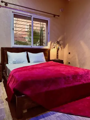 a bedroom with a large bed with a red blanket at bel appartement in Marrakech