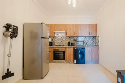 a kitchen with a stainless steel refrigerator and wooden cabinets at 3BR Luxury Stay - Hivernage- Pool View - Parking Near M Avenue & Rail in Marrakech