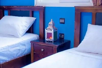 a bedroom with two beds and a night stand with a clock at Riad Palm and Pool 2 in Marrakech