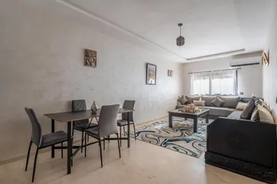 a living room with a table and a couch at Cocon Sable piscine et parking in Marrakech