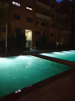 an empty swimming pool at night in front of a building at Cocon Sable piscine et parking in Marrakech