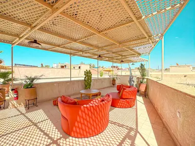 an outdoor patio with orange chairs and tables and a roof at Riad Timija in Marrakech