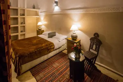 a bedroom with a bed and a table and a chair at Riad Light Of Sun in Marrakech