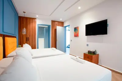 a bedroom with two white beds and a flat screen tv at Triplex luxe marrakech in Marrakech
