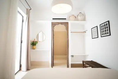 a bedroom with white walls and a mirror at Riad Dar Mimi in Marrakech