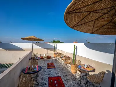 a patio with chairs and tables and an umbrella at Riad Loriental And Spa in Marrakech