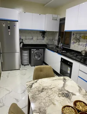 a kitchen with white cabinets and a table and appliances at Séjour agréable à marrakech in Marrakech