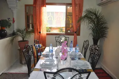 a table with chairs and a table with flowers on it at Appartement Andalou in Marrakech