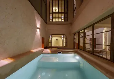 a large swimming pool in a room with windows at DarNiama - 3 Suites & Private Pool - Gueliz Center in Marrakech