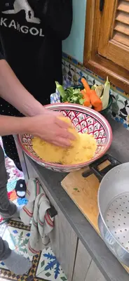 a person preparing food in two plates on a counter at atelier de cuisine in Marrakech