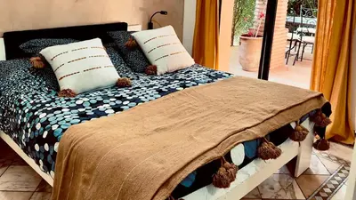 a bed with a blanket and pillows on it at Appart villa de luxe avec 5 piscines in Marrakech