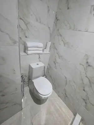 a white bathroom with a toilet and towels at Appart-by-Ily-Avenue M VI -Agdal in Marrakech