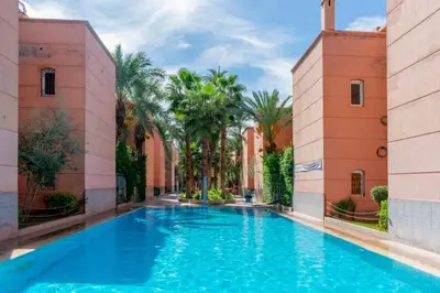a swimming pool in the middle of a building with palm trees at Al Qaria Syahia Duplex Moufid in Marrakech