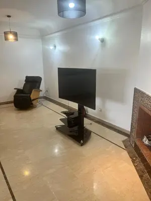 a living room with a flat screen tv and a chair at Prestigieux Appart hivernage in Marrakech
