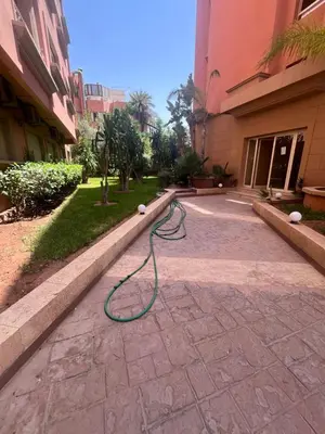 a green hose laying on a sidewalk next to a building at Prestigieux Appart hivernage in Marrakech