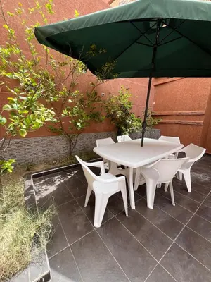 a white table and chairs with a green umbrella at Villa with private pool in Tamensourt