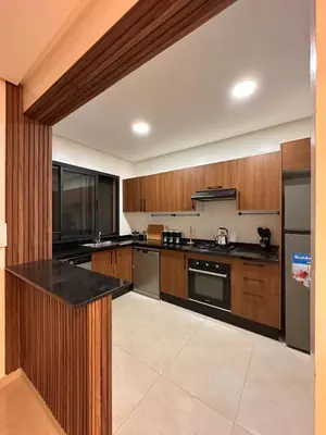 a large kitchen with wooden cabinets and black counter tops at appartement luxueux au centre vlle avec piscine in Marrakech