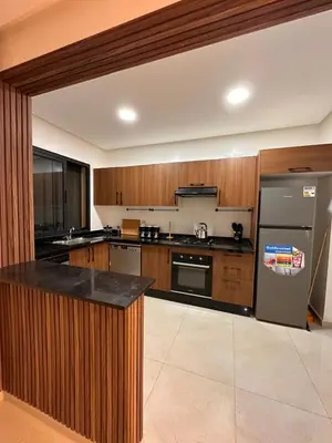 a large kitchen with wooden cabinets and a refrigerator at appartement luxueux au centre vlle avec piscine in Marrakech