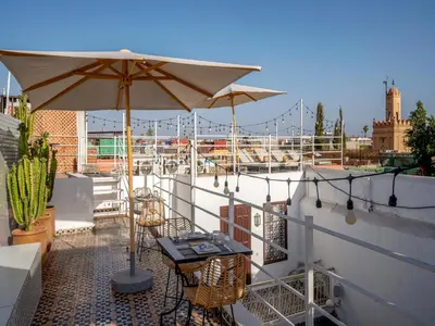 a patio with a table and umbrella on a balcony at Riad Fleur De Sable in Marrakech