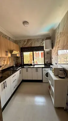 a large kitchen with white cabinets and a window at Sofia Palmeraie - High standing in Marrakech