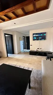 a living room with a table and a tv on the wall at Sofia Palmeraie - High standing in Marrakech