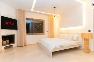 a white bedroom with a bed and a fireplace at Villa Meraki in Marrakech