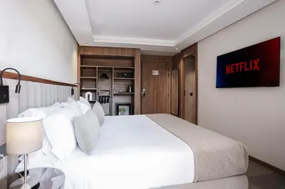a bedroom with a white bed and a tv on the wall at NearYo Hotels in Marrakech