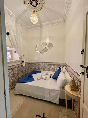 a bedroom with a bed with blue and white pillows at Dar Salomi in Marrakech