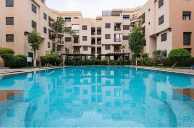 a large swimming pool in front of some buildings at Résidence riad jawhara in Marrakech