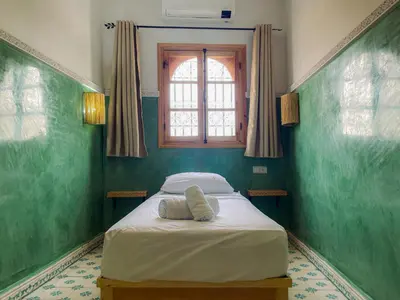 a bed in a green room with a window at Antaki retreat Marrakech in Marrakech