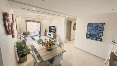 a dining room and living room with a table and chairs at Central Cozy Kesh - Pool - Terrace in Marrakech