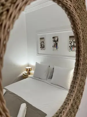 a mirror reflecting a bed with white sheets and pillows at RIAD Al QARYA 4 chambres in Marrakech