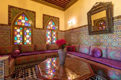 a living room with a purple couch with a table and stained glass windows at L Mansion Villa in Najem