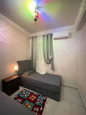 a small bedroom with a bed and a lamp at lUXEE APPARTEMENTN BELLE in Marrakech