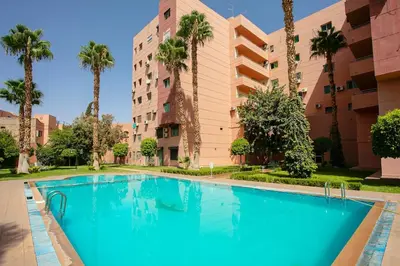 a swimming pool in front of a building with palm trees at Luxury apartment with pool in Marrakech