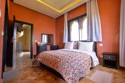 a bedroom with a bed with orange walls and a window at Luxury Villa in Marrakech