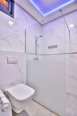 a white bathroom with a toilet and a shower at Bel appartement central in Marrakech