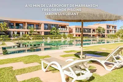 a couple of chairs and an umbrella next to a pool at Alba cosy - 3 piscines, Wifi HD, Parc de jeux in Marrakech