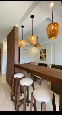 a kitchen with a table with stools and lights at Alba cosy - 3 piscines, Wifi HD, Parc de jeux in Marrakech