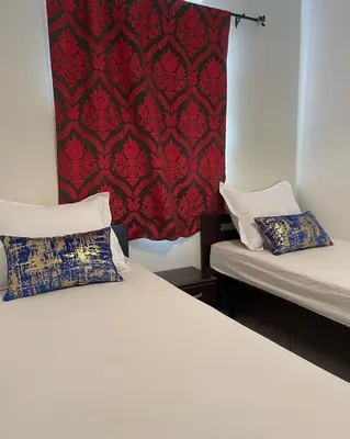 two beds in a room with a red curtain at Riad butterfly marrakech 2 in Marrakech