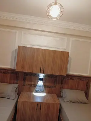 a room with two beds and a table and a chandelier at Airport view apartment Marrakech in Marrakech