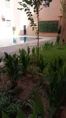 a garden with plants in front of a building at Beautiful apartment with children's pool in Marrakech