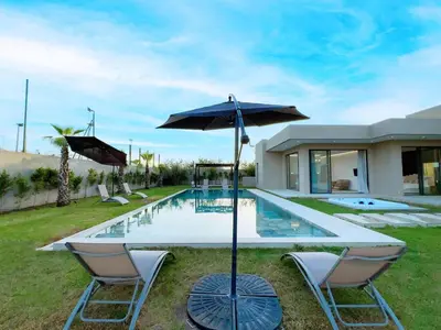a pool with two chairs and a table with an umbrella at Villa de Luxe Sans Vis-à-Vis 15 min de Marrakech in Marrakech